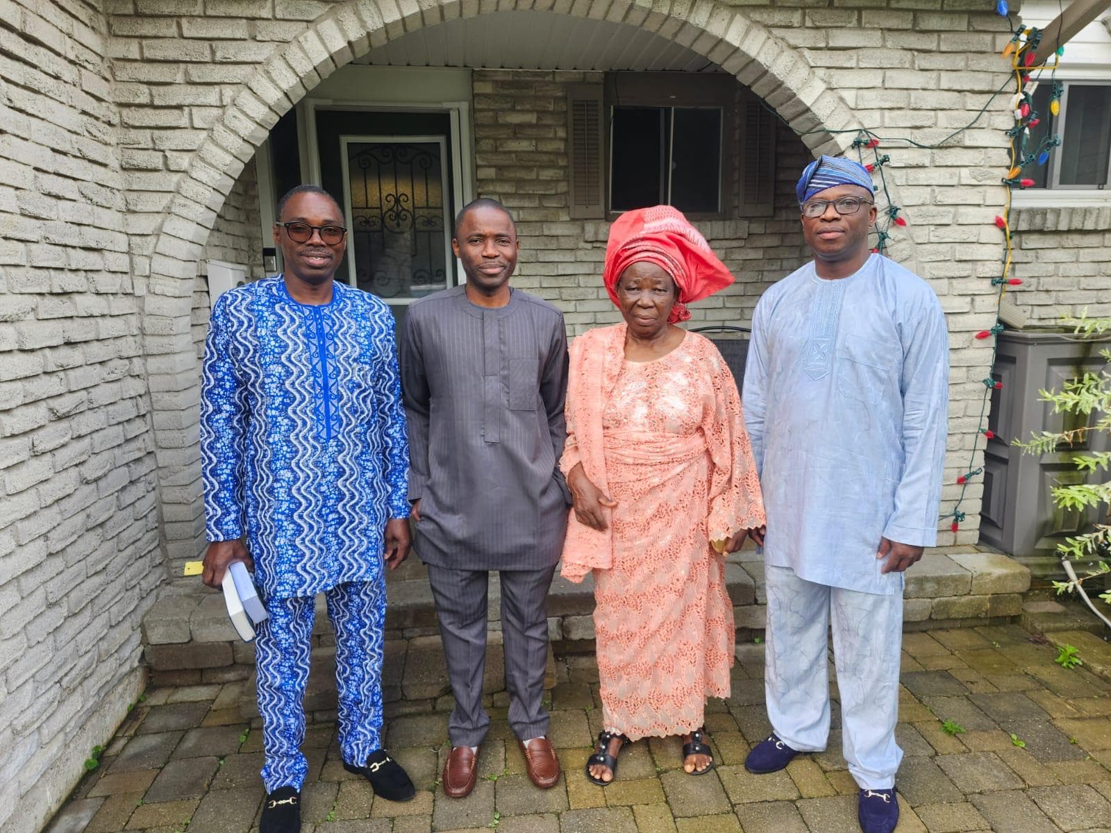 Deaconess Deborah Olubisi Oloyede in peach traditional attire standing outdoors with three family members