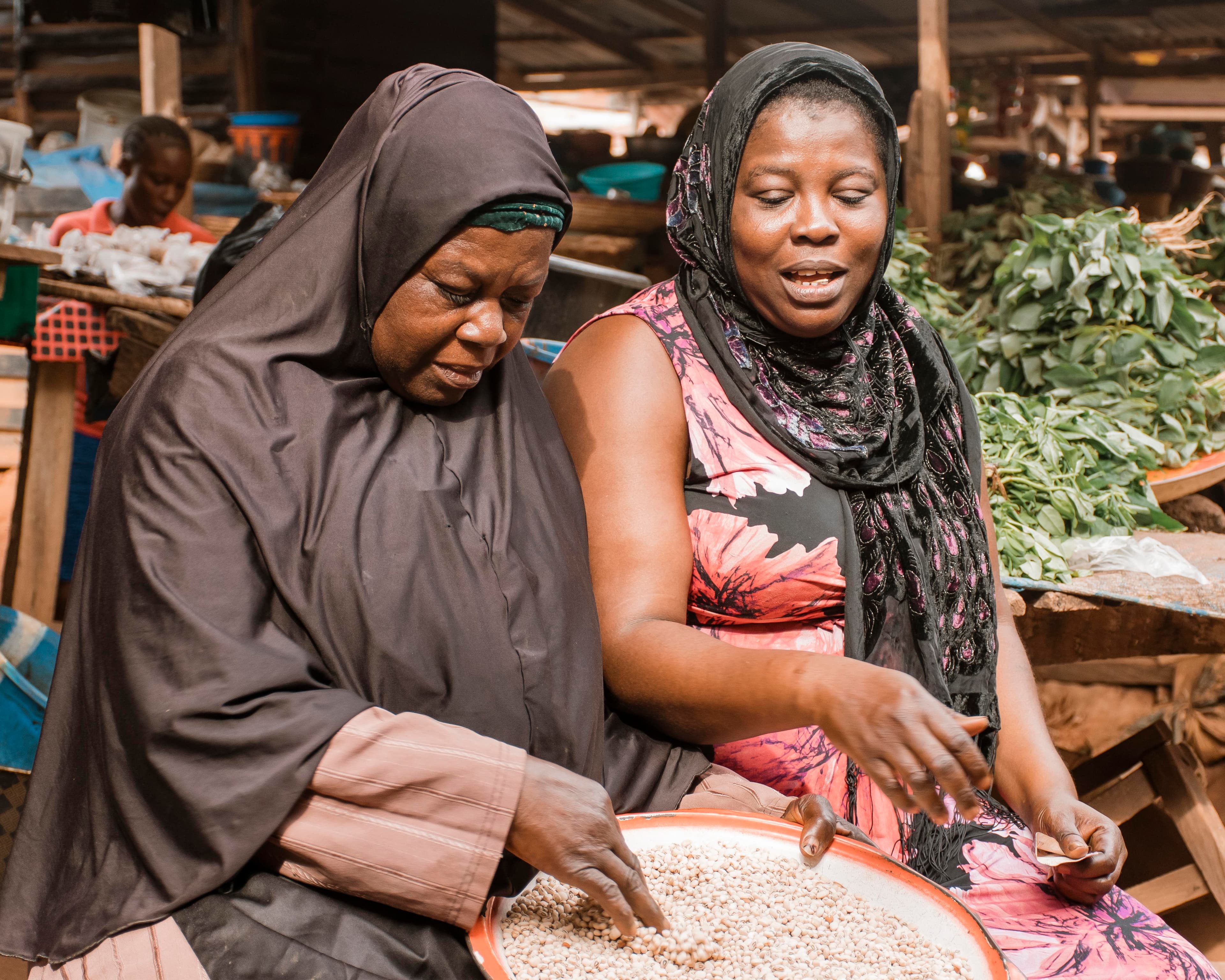 Two women working together with produce at a market